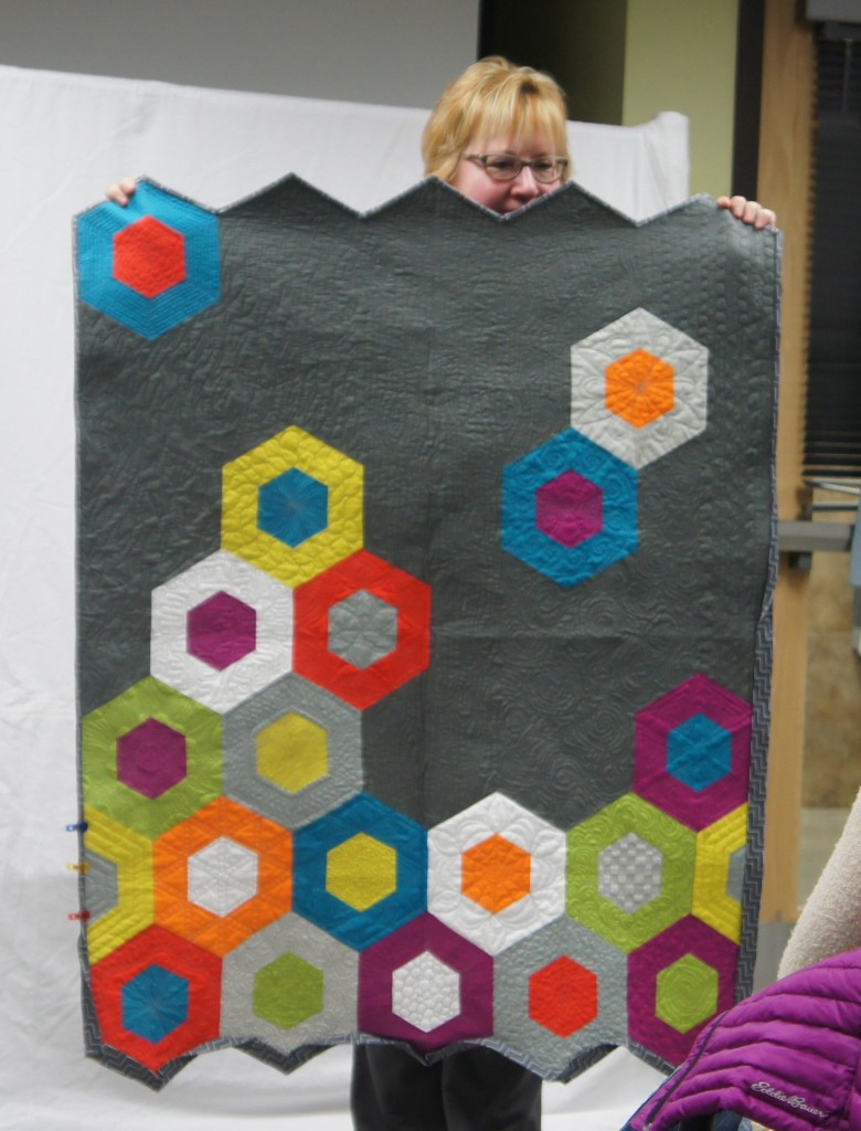 Sue– Sciencefairquilt	made	with	kit	from	Quilt	Expo.	Her	quilt	features	bright	colors, negative	space	and	a	 hexagon	pattern.