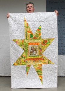 Gael showing a quilt made with a donated embroidery block.